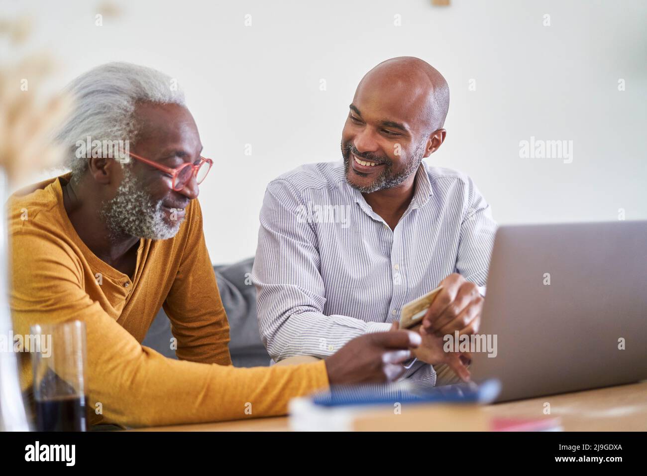 Vater und Sohn mit Laptop und Kreditkarte Stockfoto
