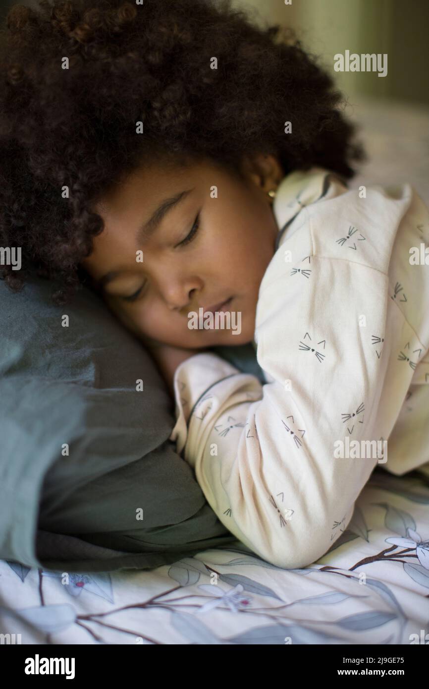 Mädchen schlafen mit Spielzeug auf dem Bett Stockfoto