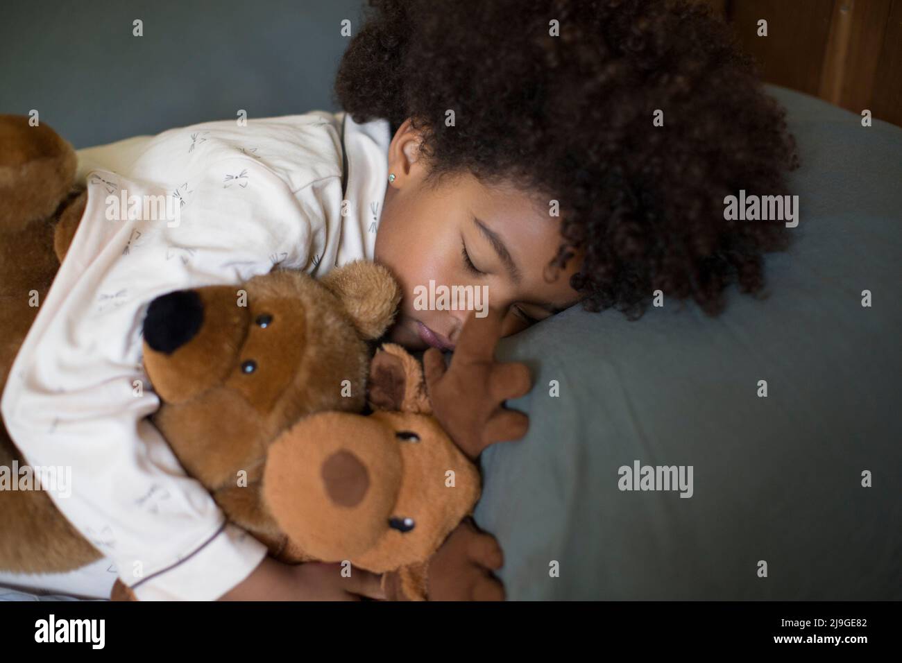 Mädchen schlafen mit Spielzeug auf dem Bett Stockfoto