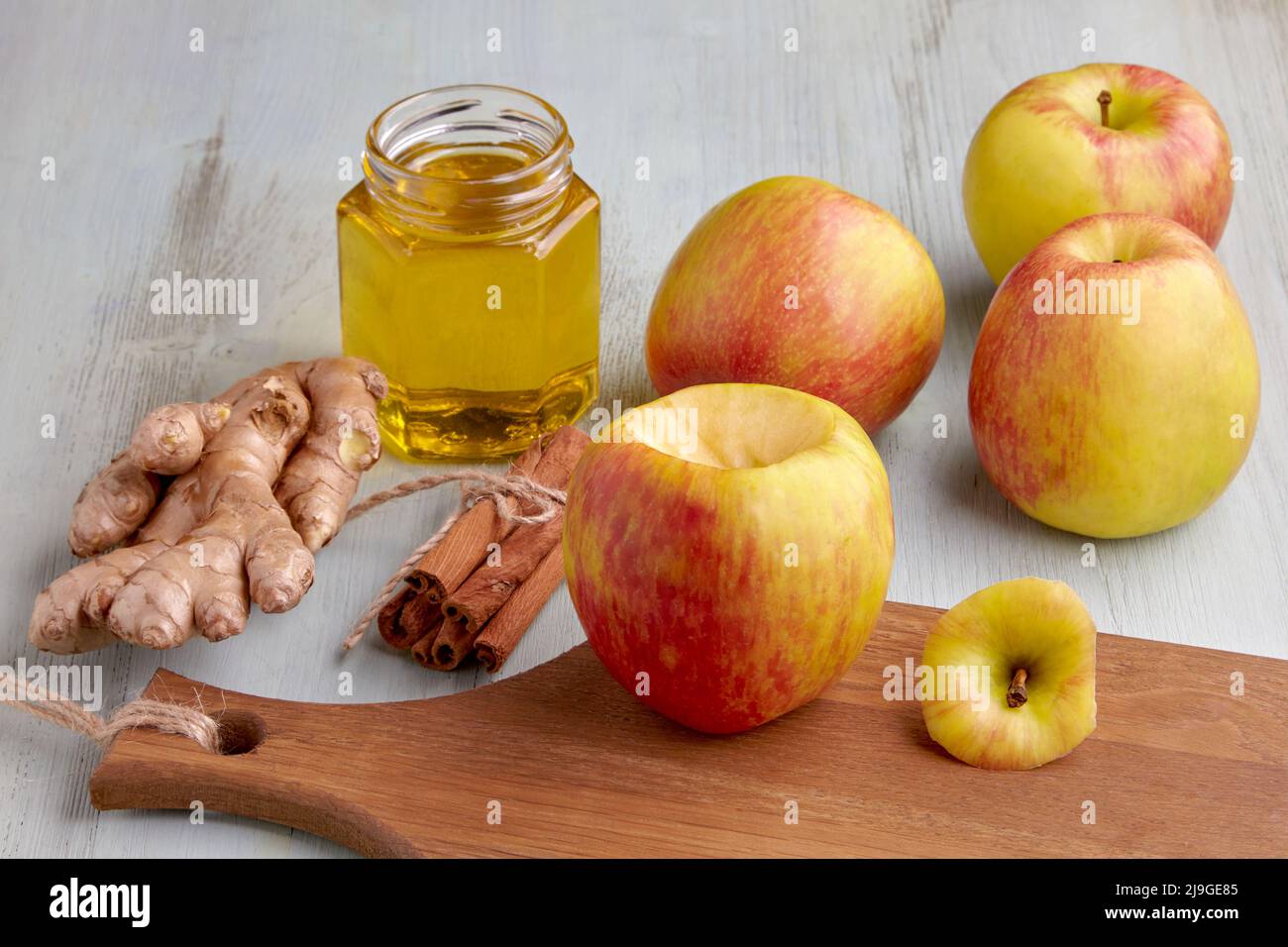 Äpfel, Zimtstangen, Ingwer und Honig auf einem hellblauen Holztisch. Kochen gebackene süße Äpfel Stockfoto