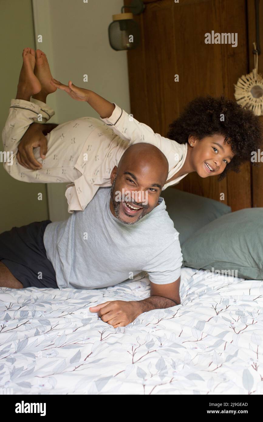Lächelnder Vater trägt seine Tochter auf der Schulter im Schlafzimmer Stockfoto