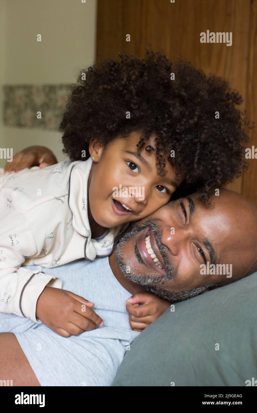 Lächelnder Vater und Tochter entspannen sich auf dem Bett Stockfoto