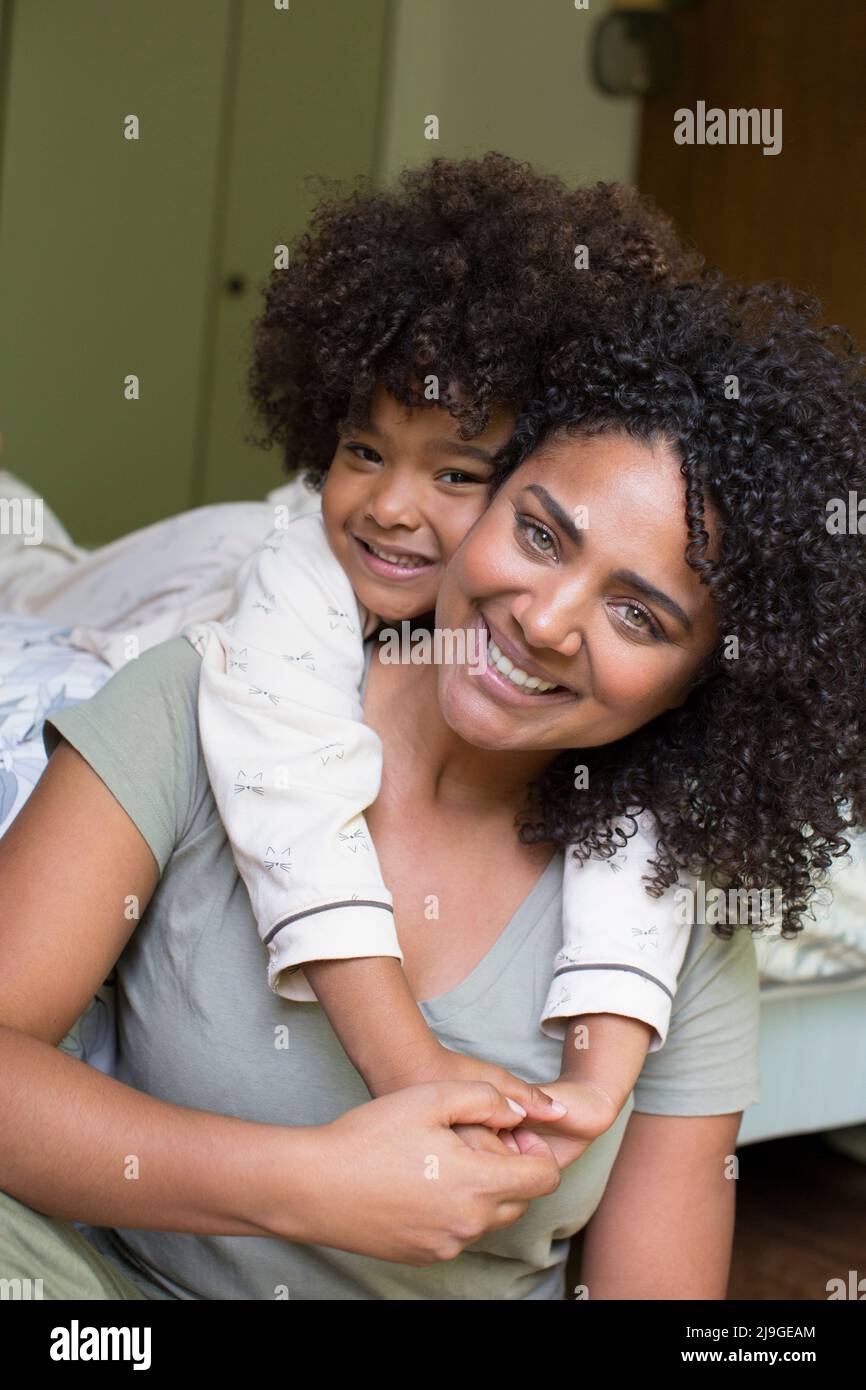 Lächelnde Tochter umarmt ihre Mutter im Schlafzimmer Stockfoto