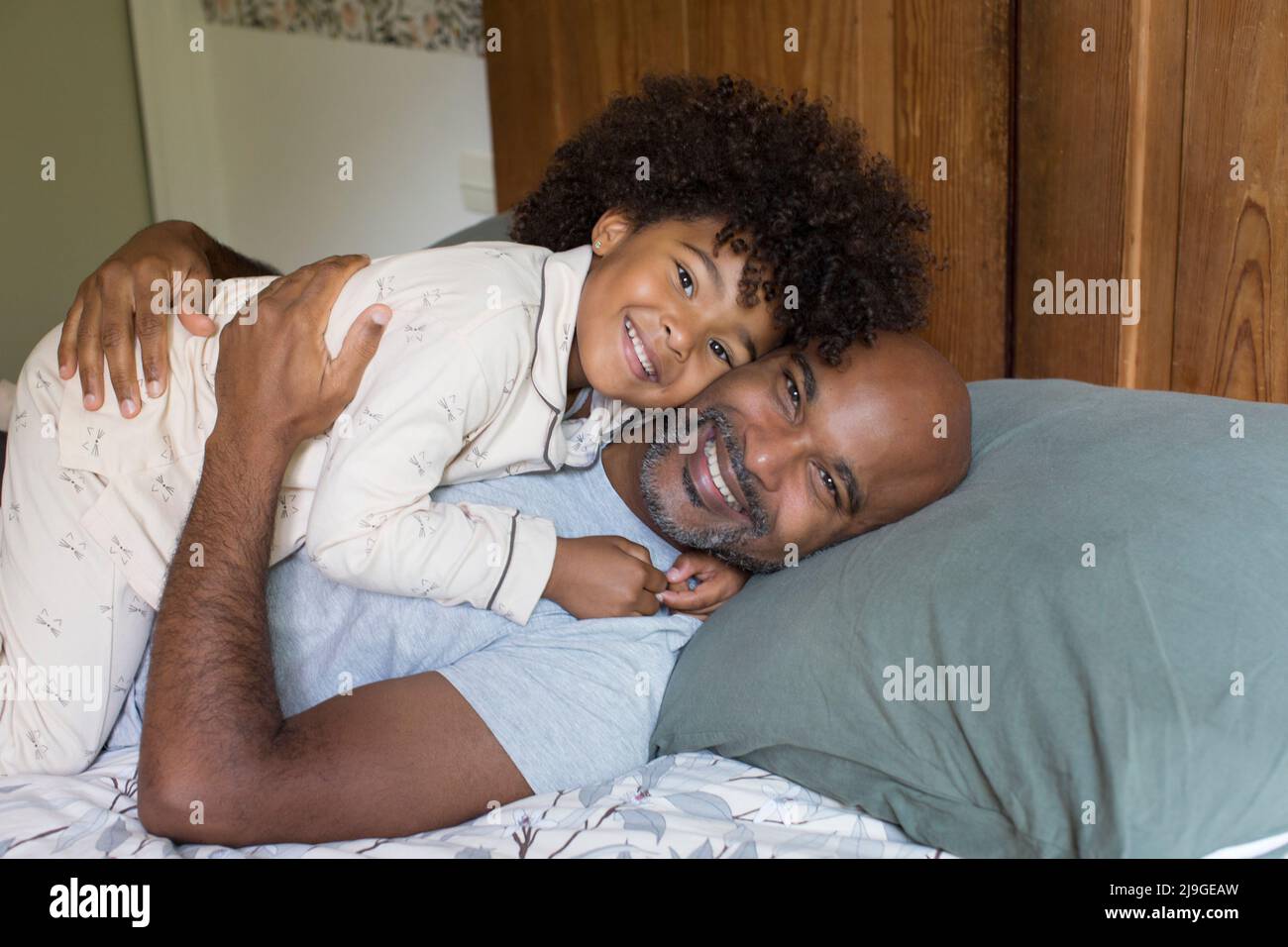 Lächelnder Vater und Tochter entspannen sich auf dem Bett Stockfoto
