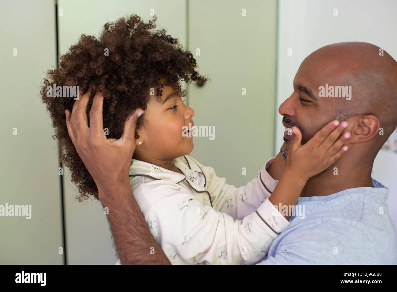 Tochter berührt das Gesicht seines Vaters und schaut sich an Stockfoto