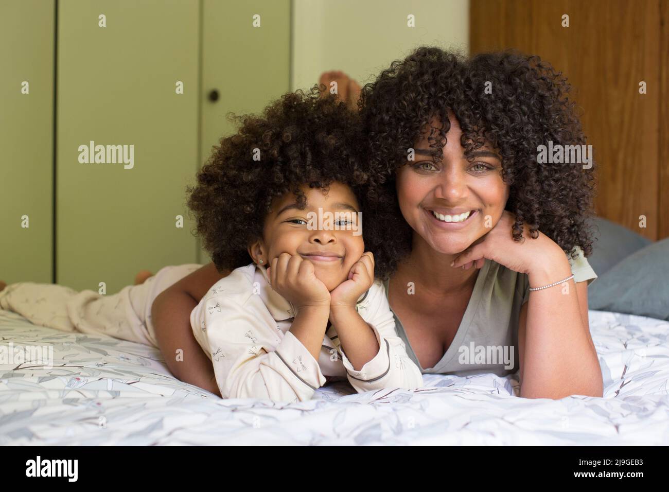 Lächelnde Mutter umarmt ihre Tochter im Schlafzimmer Stockfoto