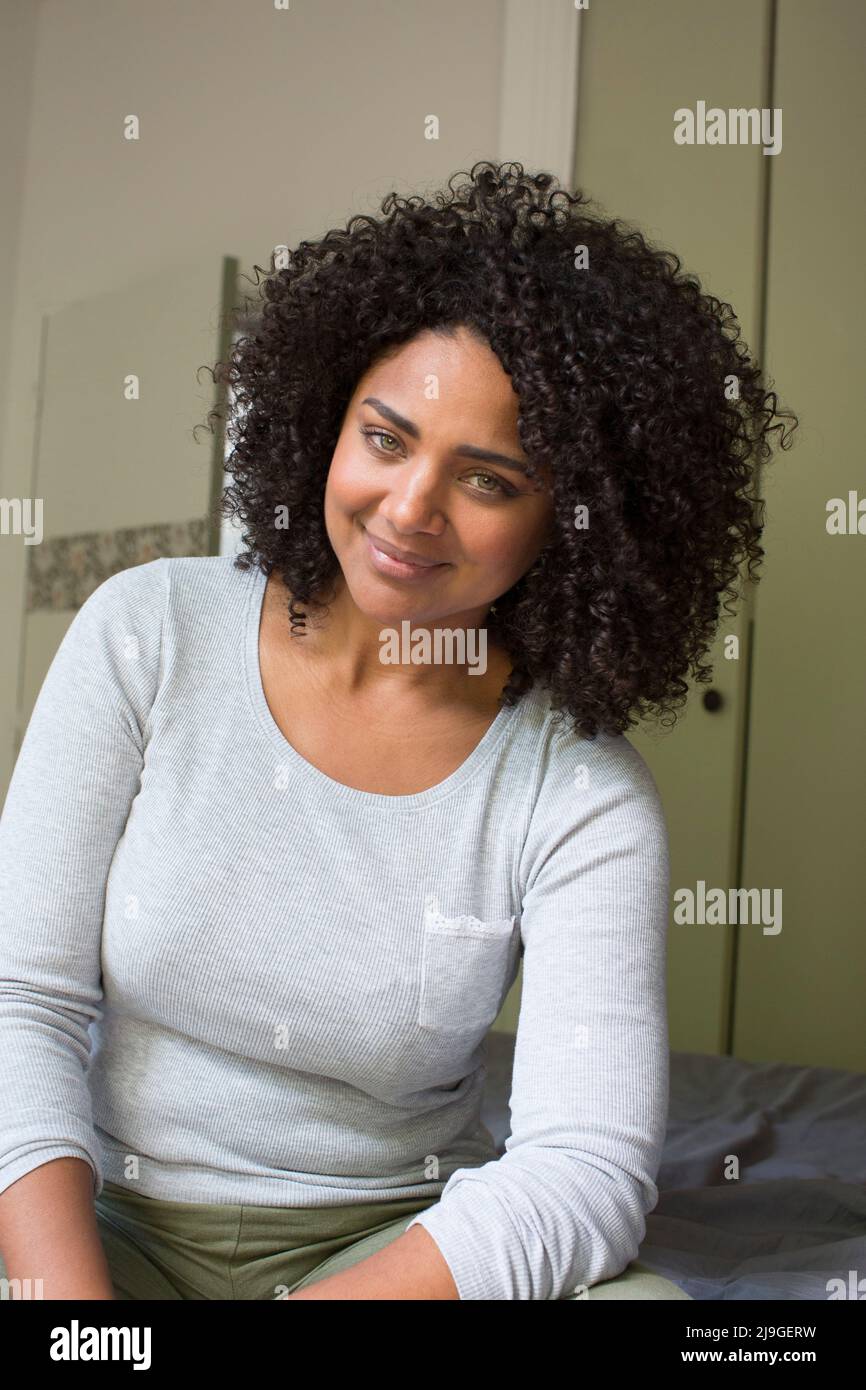 Lächelnde Frau sitzt auf Bett Stockfoto