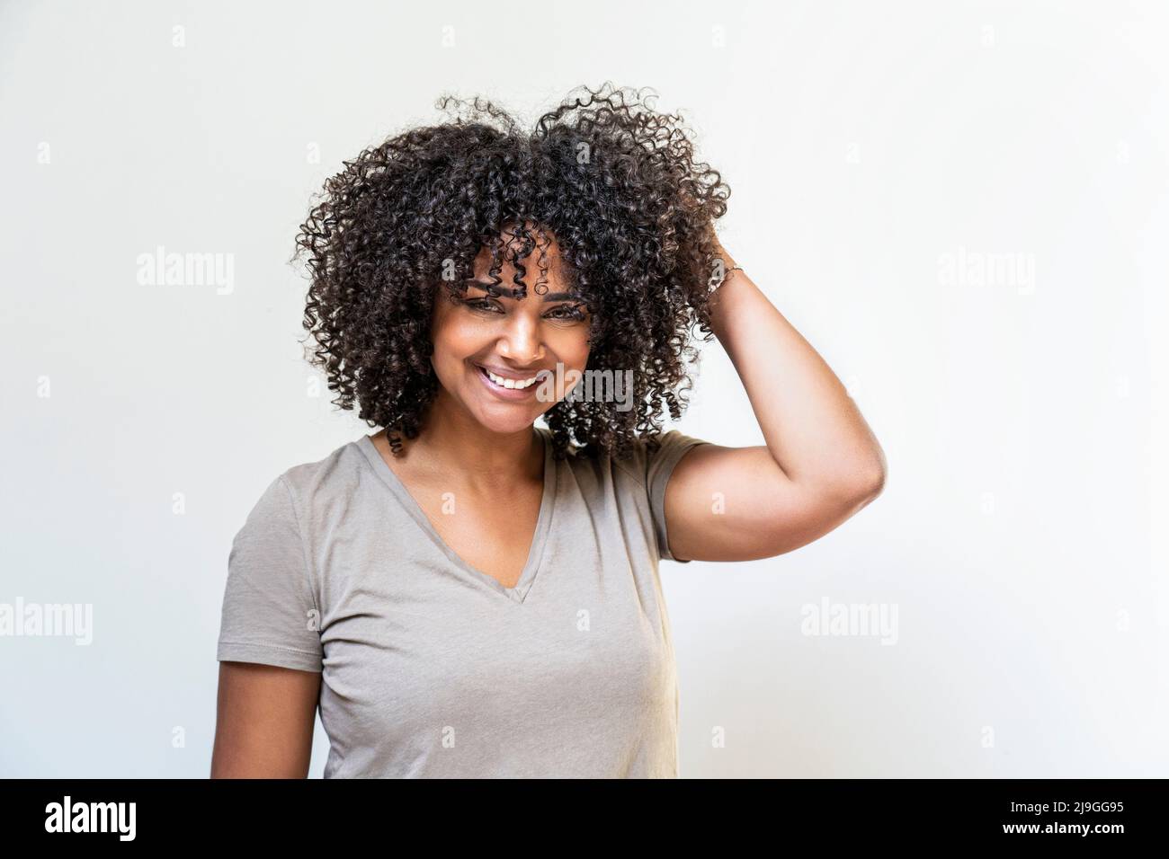 Lächelnde Frau, die gegen die weiße Wand steht Stockfoto