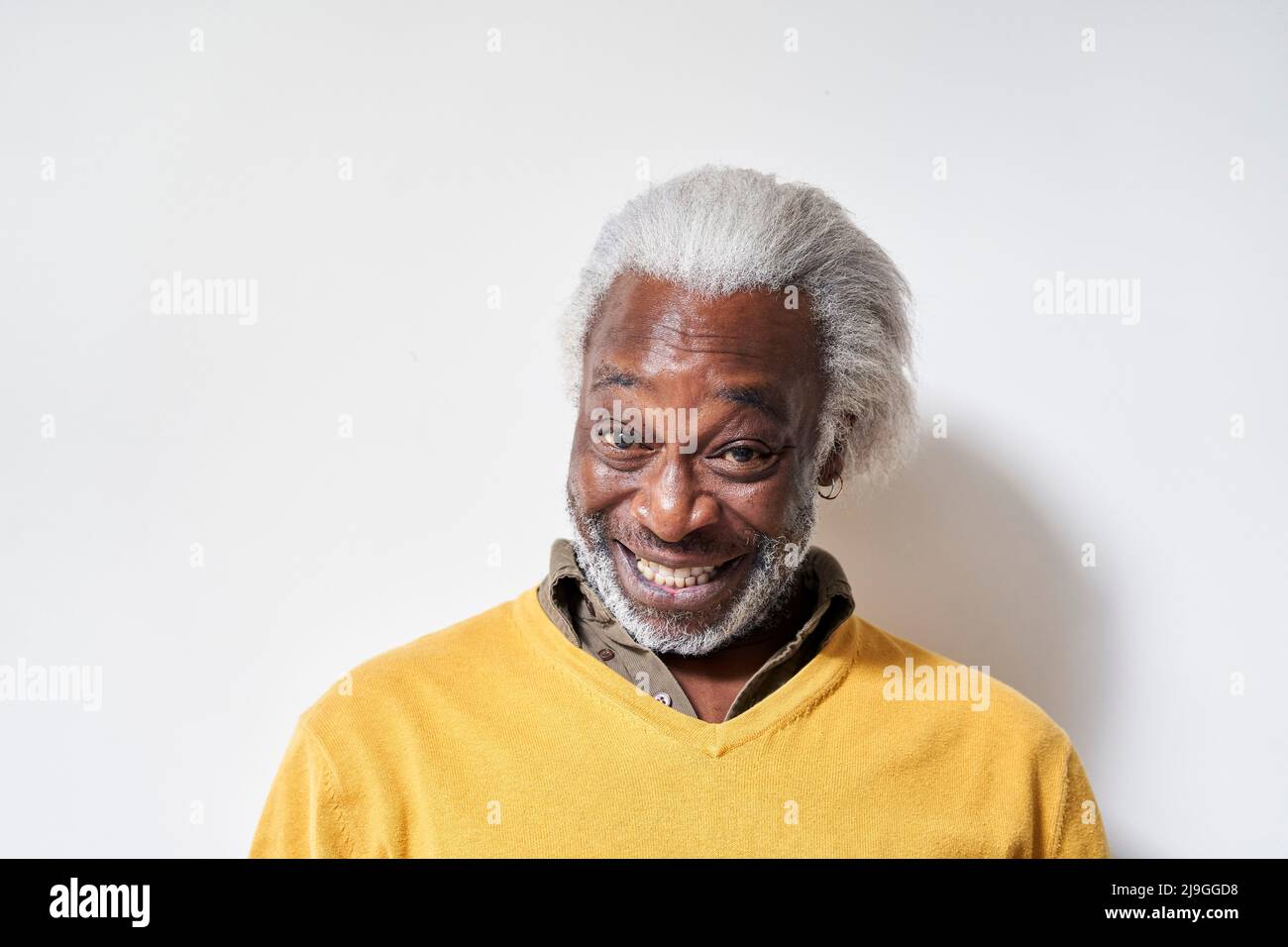 Lächelnder älterer Mann, der gegen die Wand steht Stockfoto