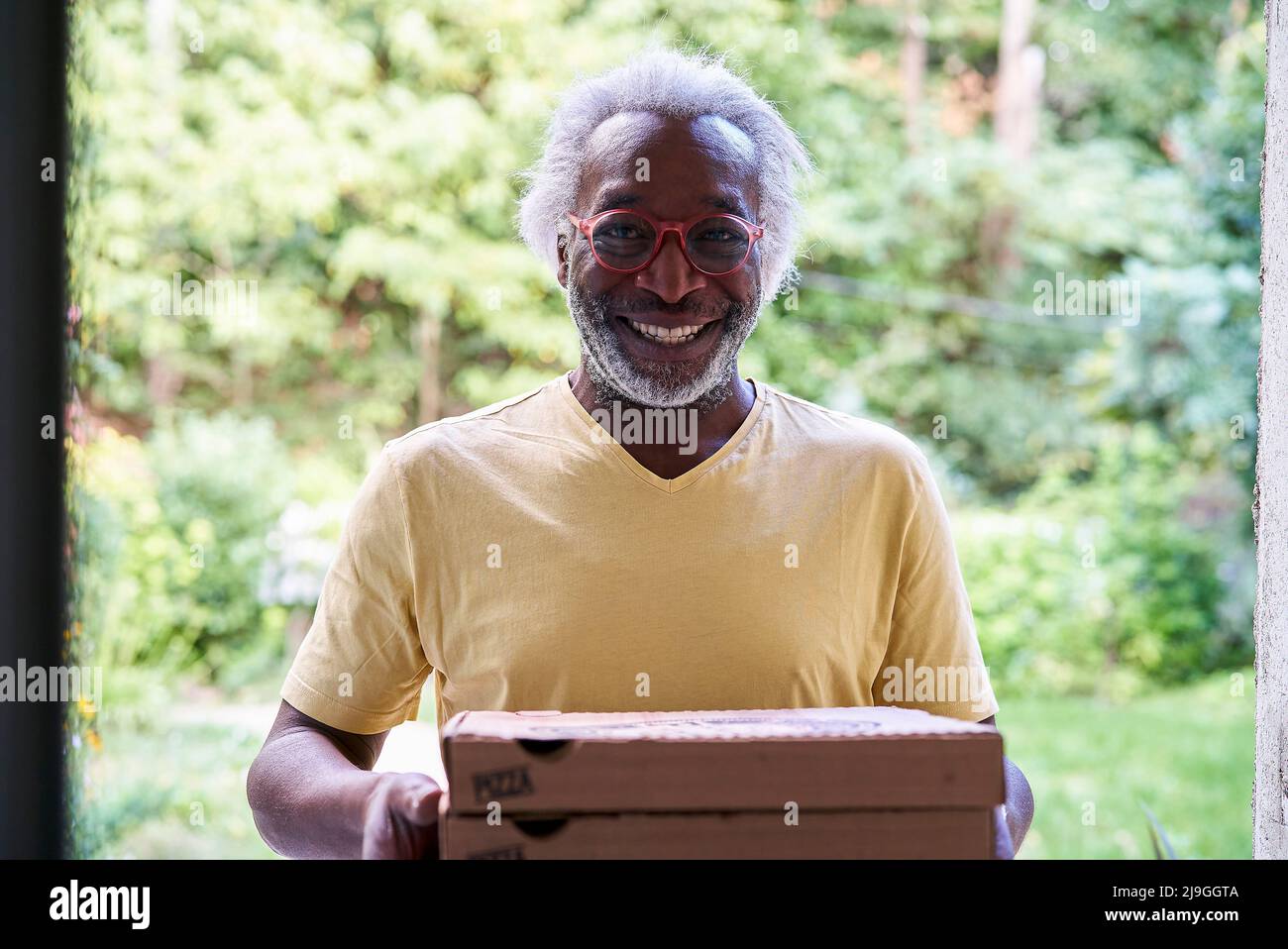 Porträt eines älteren Lieferers, der Pizza liefert Stockfoto