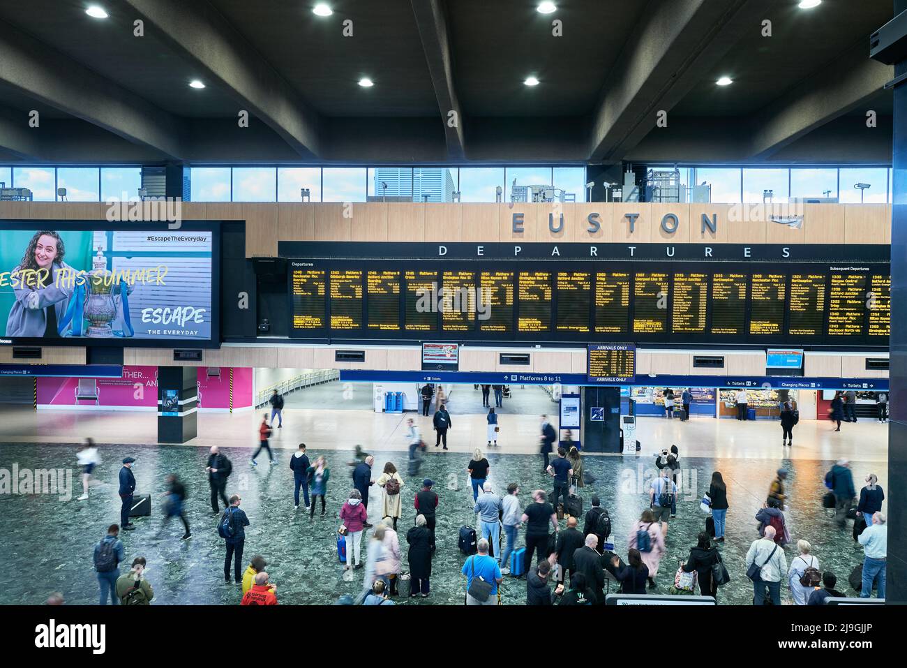 Die Fahrgäste sehen sich das Zugfahrplanbrett in der Bahnhofsgebäude am Bahnhof Waterloo, London, England an. Stockfoto