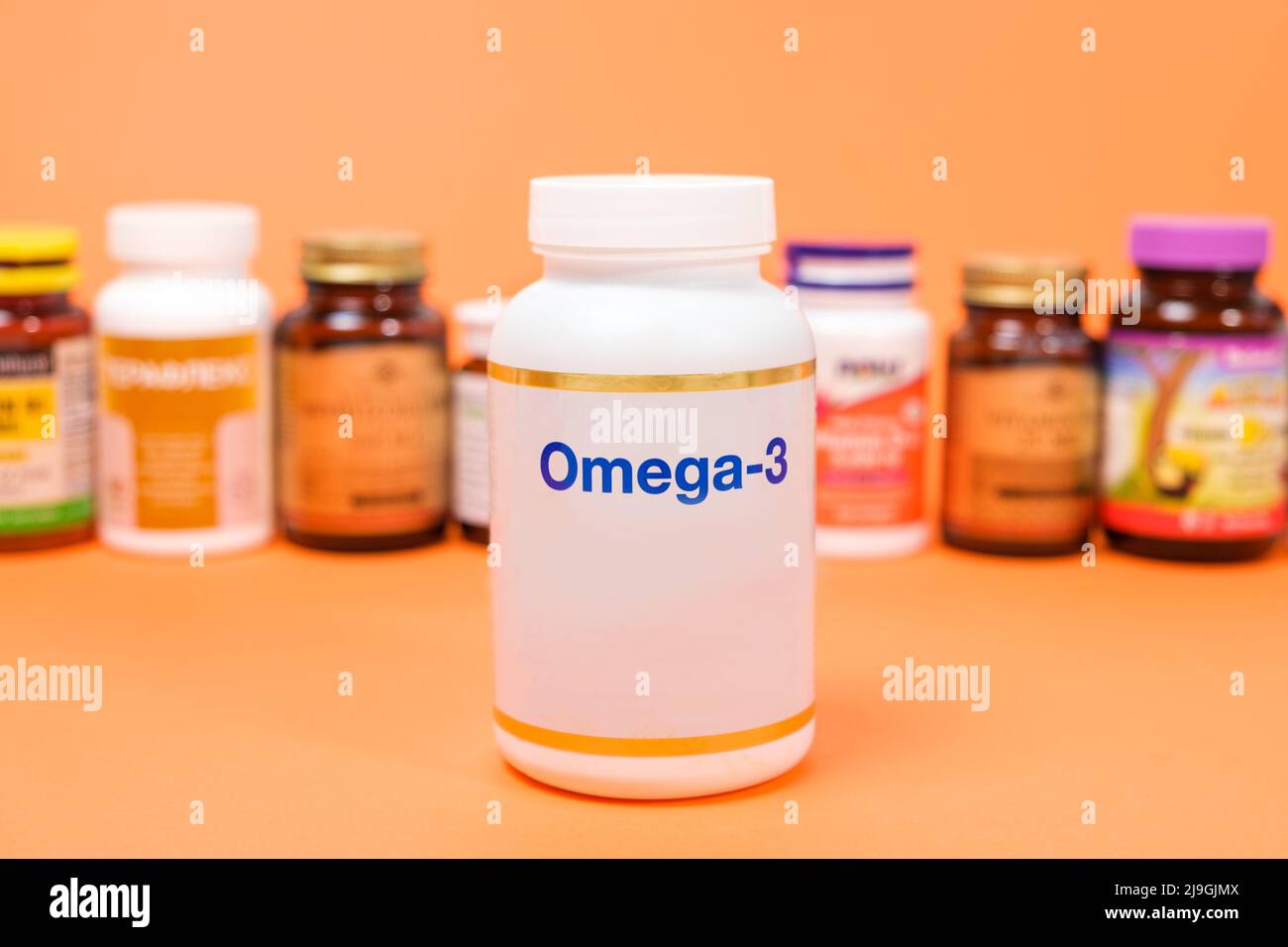 Nahrungsergänzungsmittel Omega-3 in einem weißen Glas und anderen Gläsern auf orangefarbenem Hintergrund Stockfoto