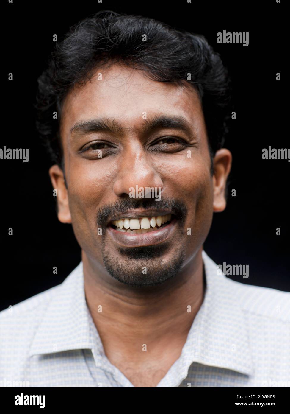 Ein ayurvedischer Arzt posiert für ein Porträt gegen einen schwarzen Backgroiund. Kairali Ayurveda Health Resort, Palakkad, Kerala, Indien. Stockfoto