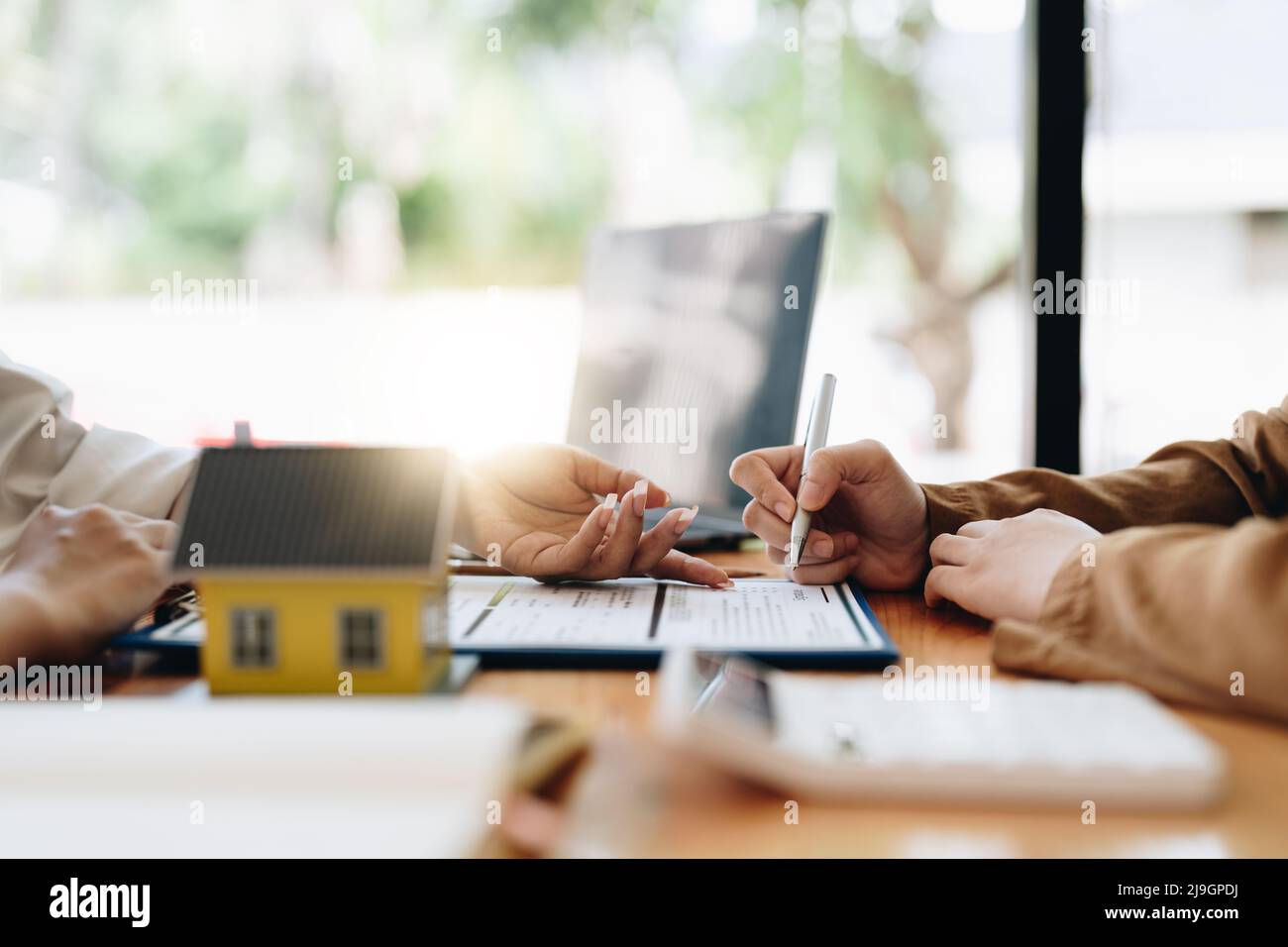 Immobilien zeigen auf die Unterzeichnung des Versicherungsvertrags und erklären den Kunden im Büro Stockfoto