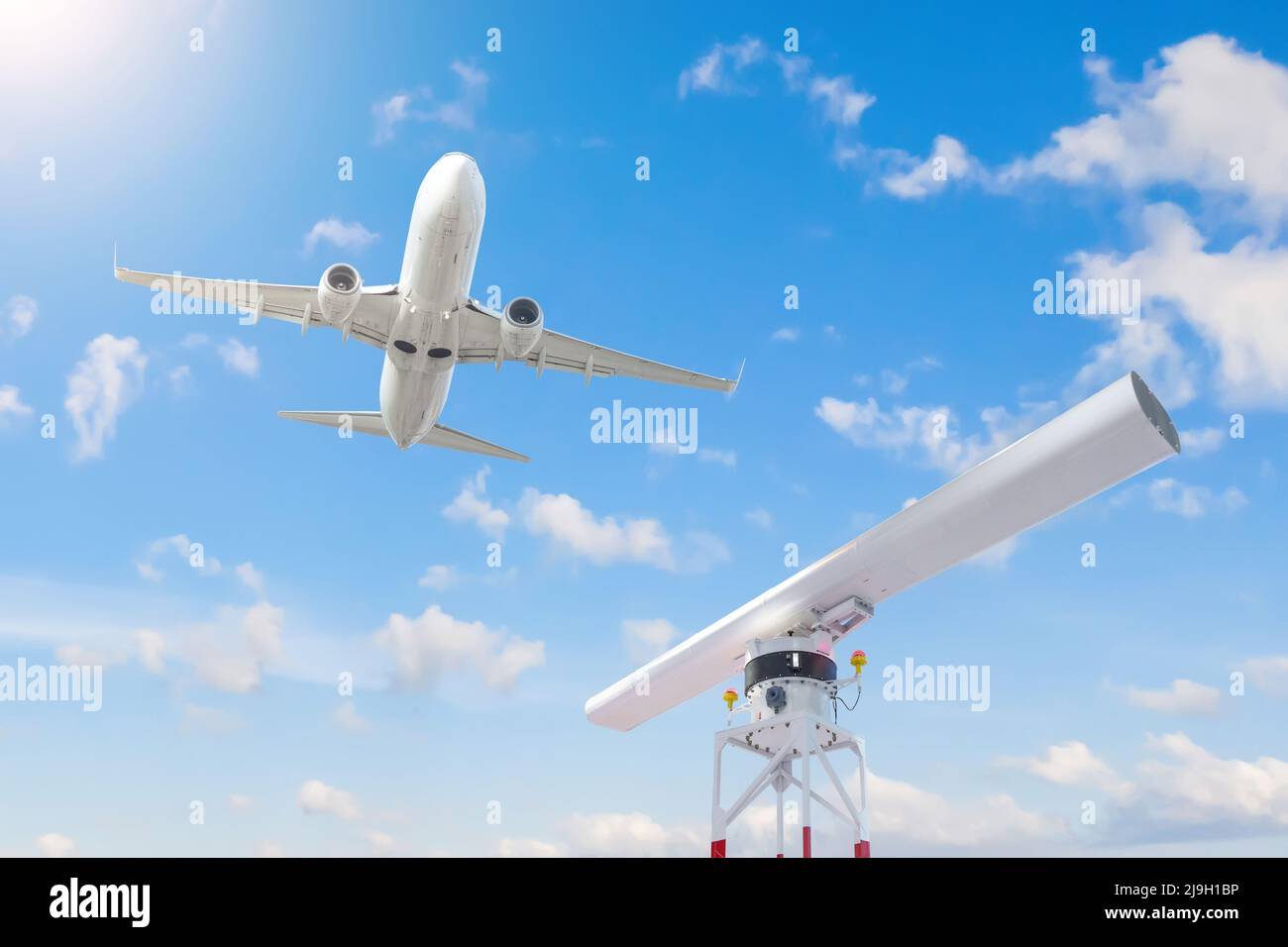 Drehlokalisator auf dem Gebiet des Flughafens und ein Passagierflugzeug, das in den Himmel abfliegt Stockfoto