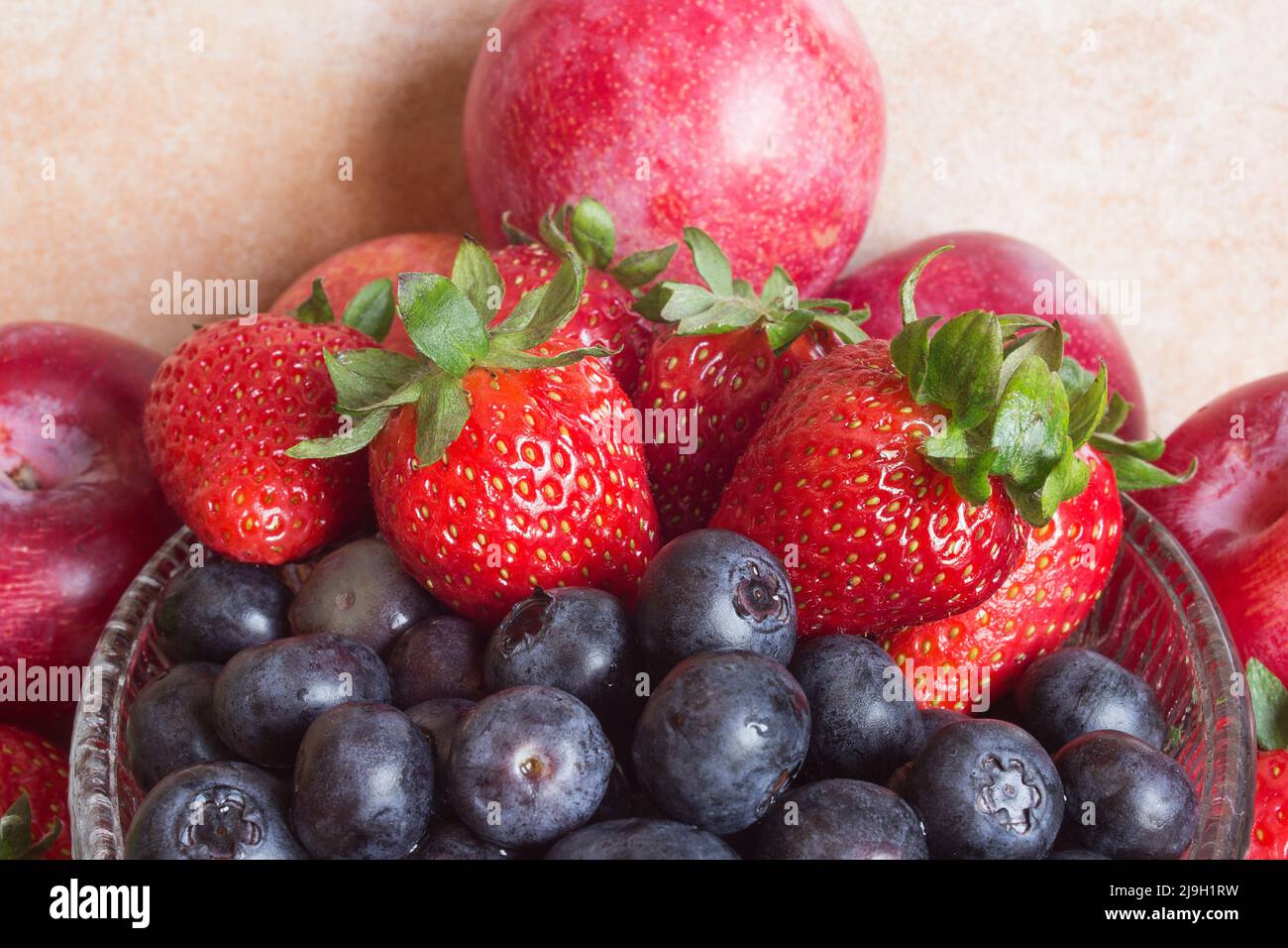 Blick von oben auf eine Nahaufnahme von Heidelbeeren, Erdbeeren und roten Pflaumen im Hintergrund. Obst und Gesundheit. Stockfoto
