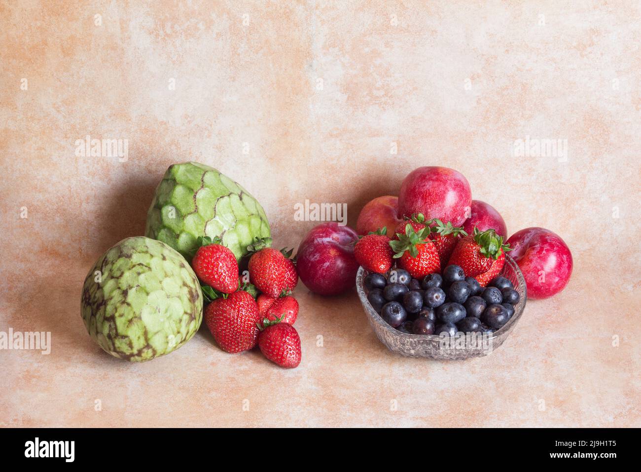 Obstgruppe auf abstraktem Studiohintergrund bestehend aus Pudding-Äpfeln, Erdbeeren, Blaubeeren und Pflaumen. Gesunde Ernährung. Stockfoto