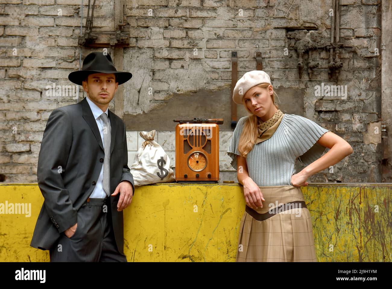 Ein junges Paar zieht sich in Kleidung im Stil von 1930 an. Sie tragen jeweils eine Waffe, während sie die Rolle des berühmten Gangsterduos Bonnie und Clyde übernehmen. Stockfoto