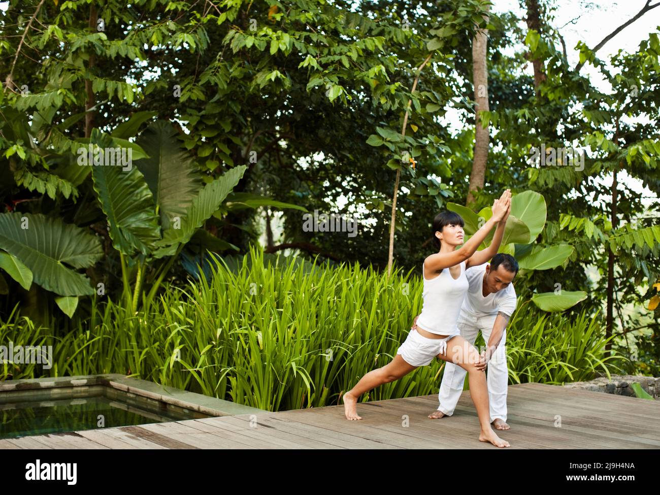 Eine Frau praktiziert Yoga während einer privaten Unterrichtsstunde in einer Pool-Villa in Kayumanis Ubud, Bali, Indonesien. Stockfoto