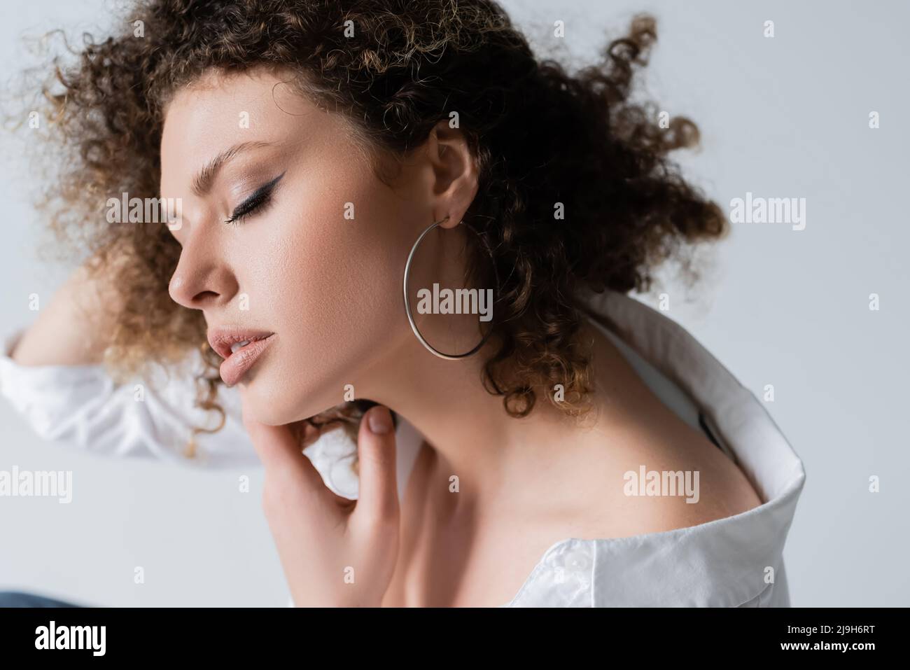 Junge Frau in Bluse berühren Hals isoliert auf weiß Stockfoto