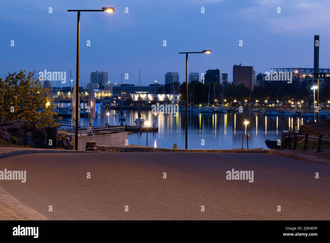 Helsinki / Finnland - 22. MAI 2022: Blick auf eine Uferpromenade mit einem ruhigen Meer und einer schlafenden Stadt im Hintergrund. Stockfoto