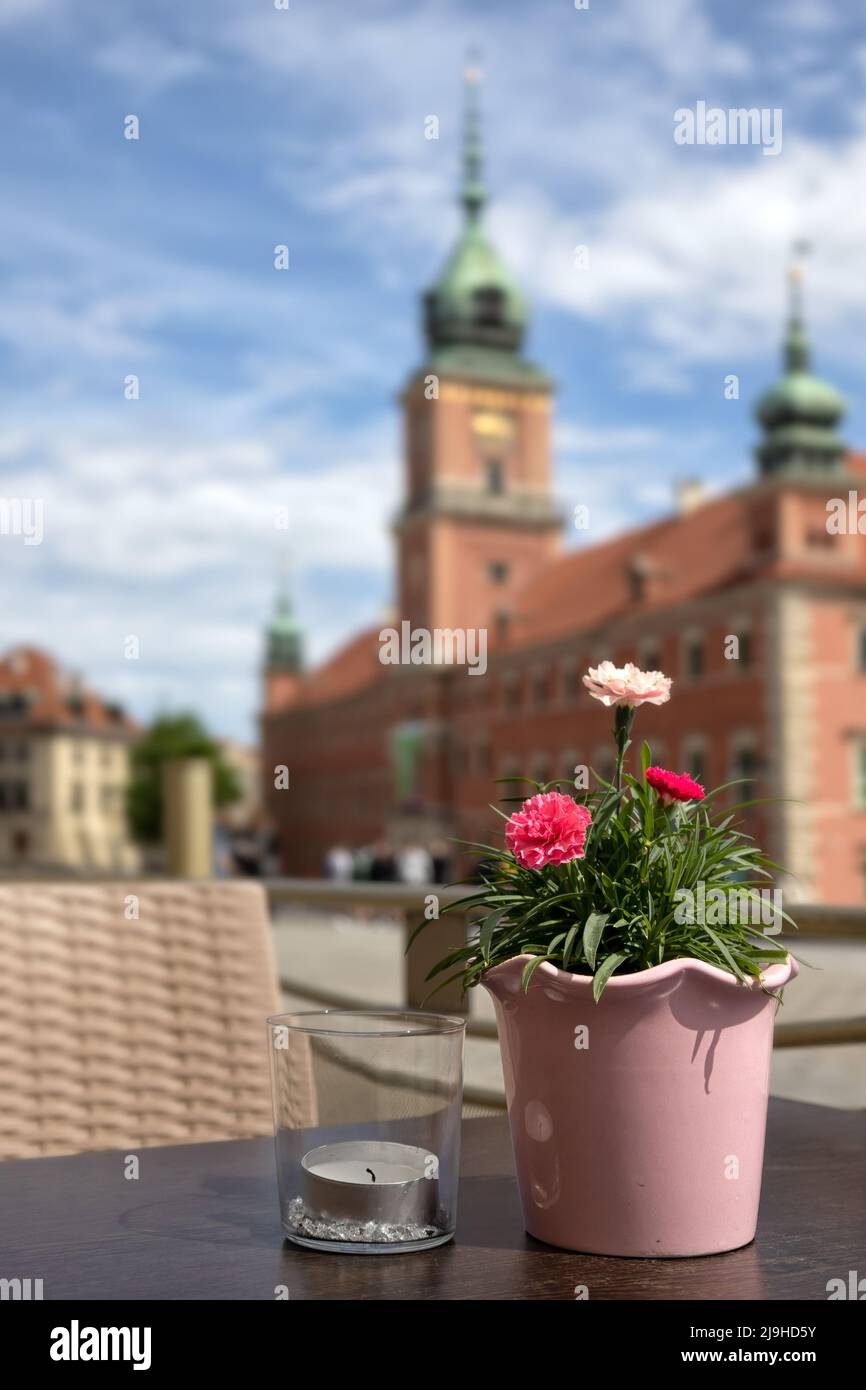 WARSCHAU, POLEN - 17. MAI 2022: Blumen auf dem Cafe-Tisch mit unschärfem Blick auf das königliche Schloss in Plac Zamkowy im Hintergrund Stockfoto