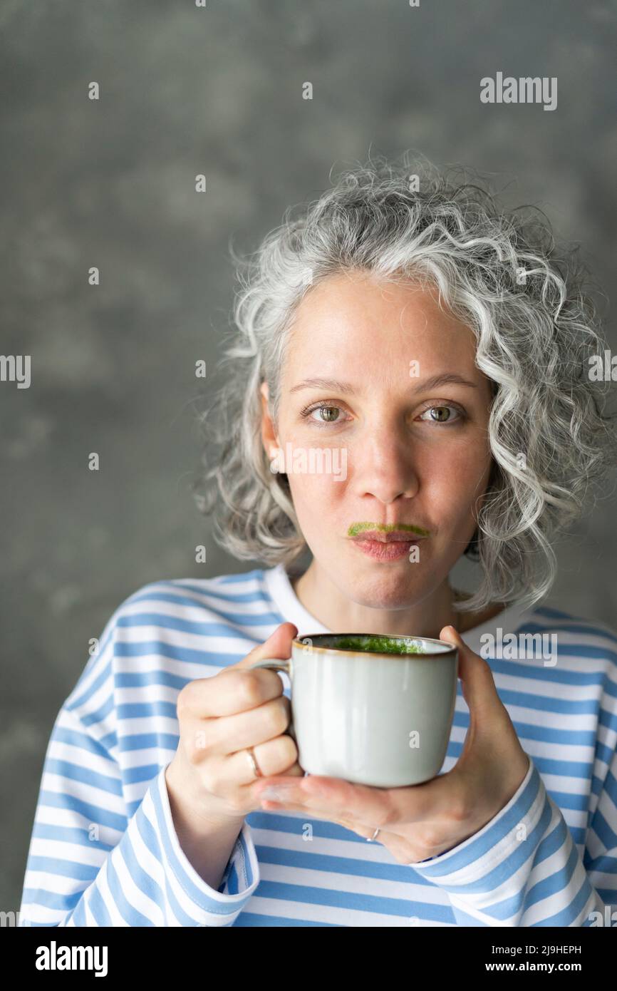 Frau mit Matcha-Tee-Schnurrbart hält Tasse Stockfoto