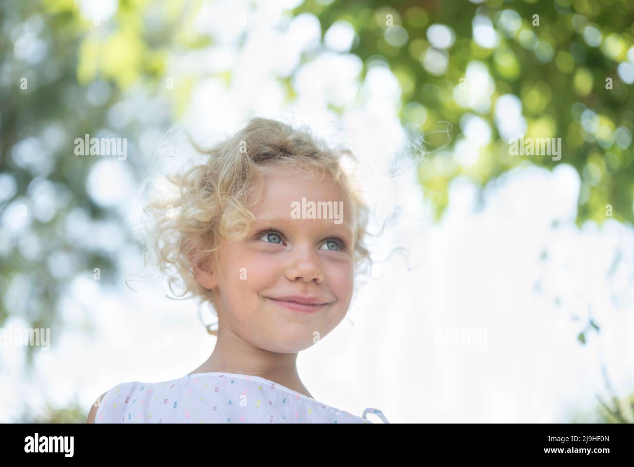Lächelndes Mädchen mit blonden Haaren im Garten Stockfoto