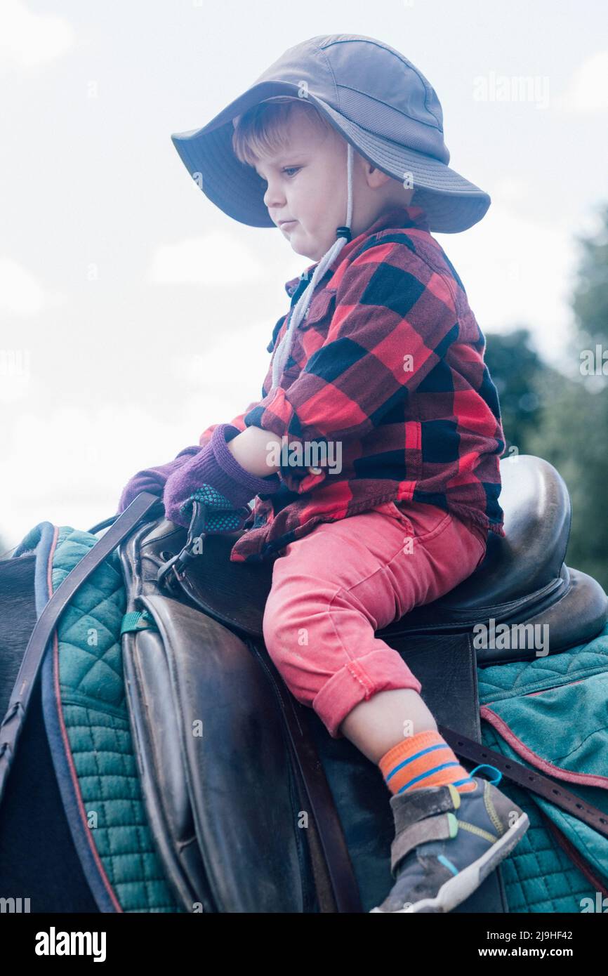 Junge mit Hut auf Pferd sitzend Stockfoto