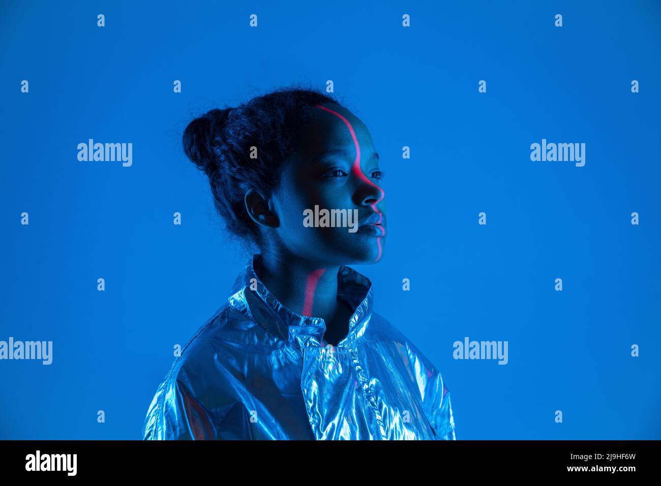 Laserlicht fällt auf das Gesicht der Frau vor blauem Hintergrund Stockfoto