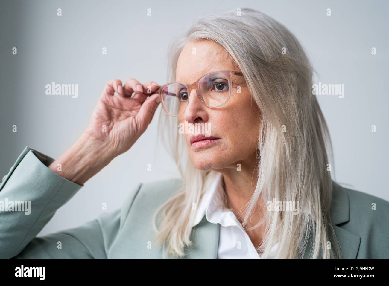 Besorgte Geschäftsfrau mit Brille vor weißem Hintergrund Stockfoto