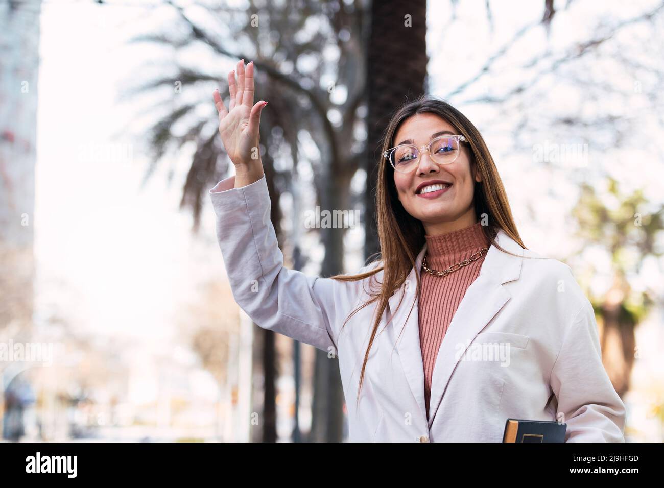Glückliche Frau mit Brillen winkende Hand Stockfoto