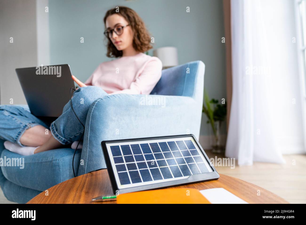 Solarbatterieladegerät auf dem Tisch mit Geschäftsfrau im Hintergrund, die zu Hause arbeitet Stockfoto