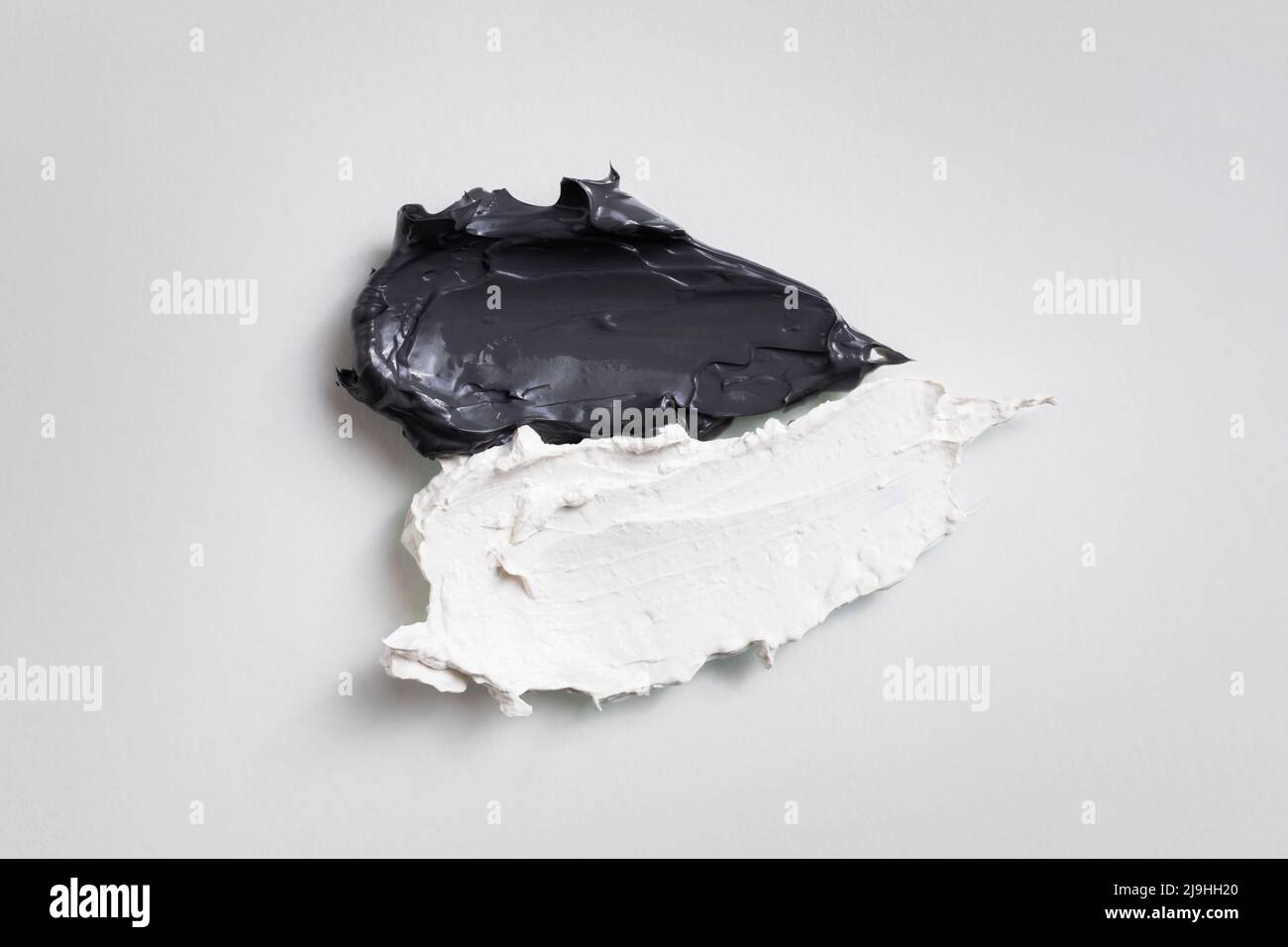 Schwarz-weiße Gesichtsmasken aus Ton, isoliert auf grauem Untergrund. Stockfoto