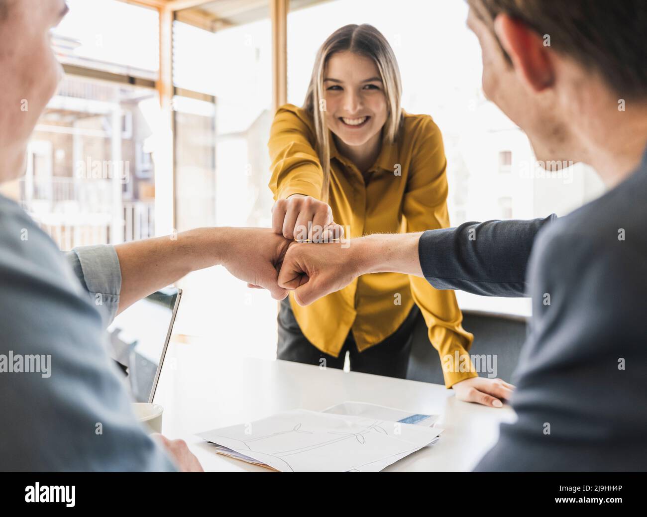 Glückliches Geschäftsteam, das die Fäuste im Büro anfasst Stockfoto