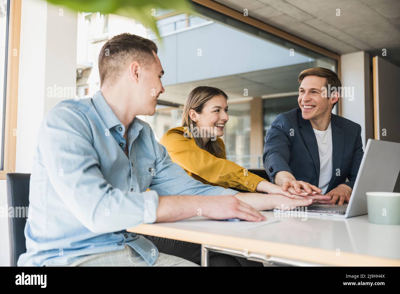 Glückliches Geschäftsteam, das im Büro die Hände stapelt Stockfoto