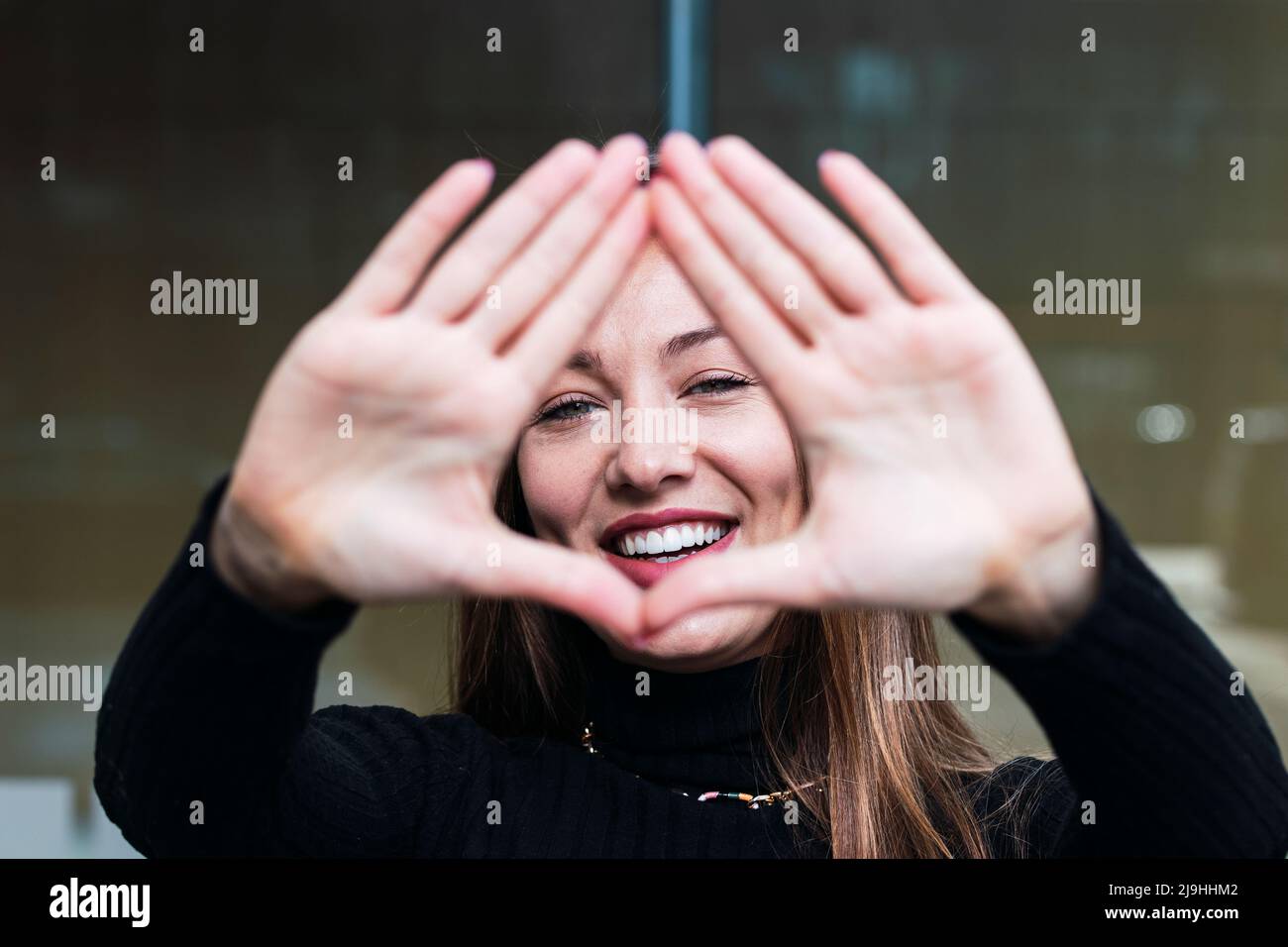 Glückliche junge Frau gestikuliert Fingerrahmen Stockfoto