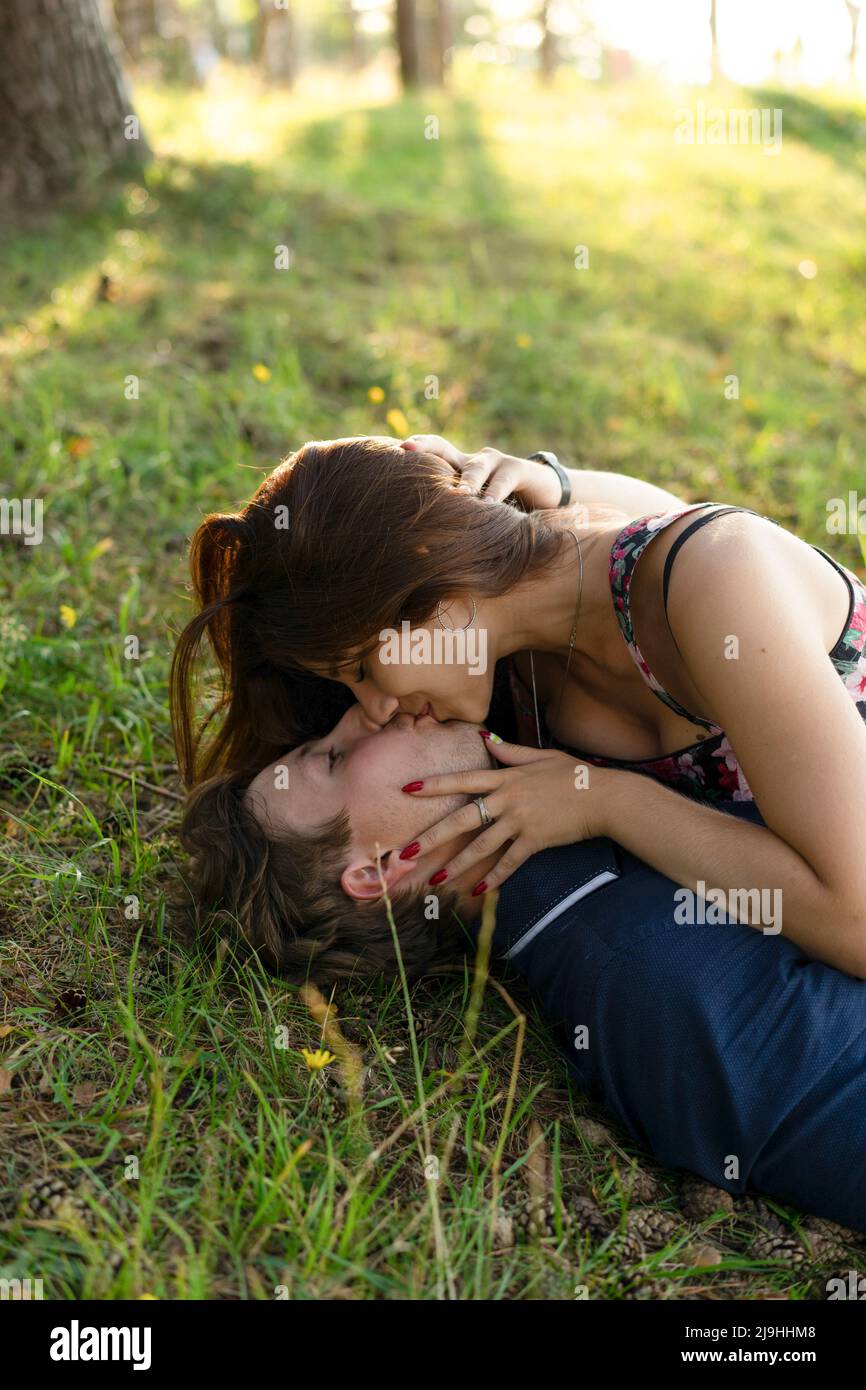 Glückliches Paar küsst sich gegenseitig auf Gras liegend Stockfoto