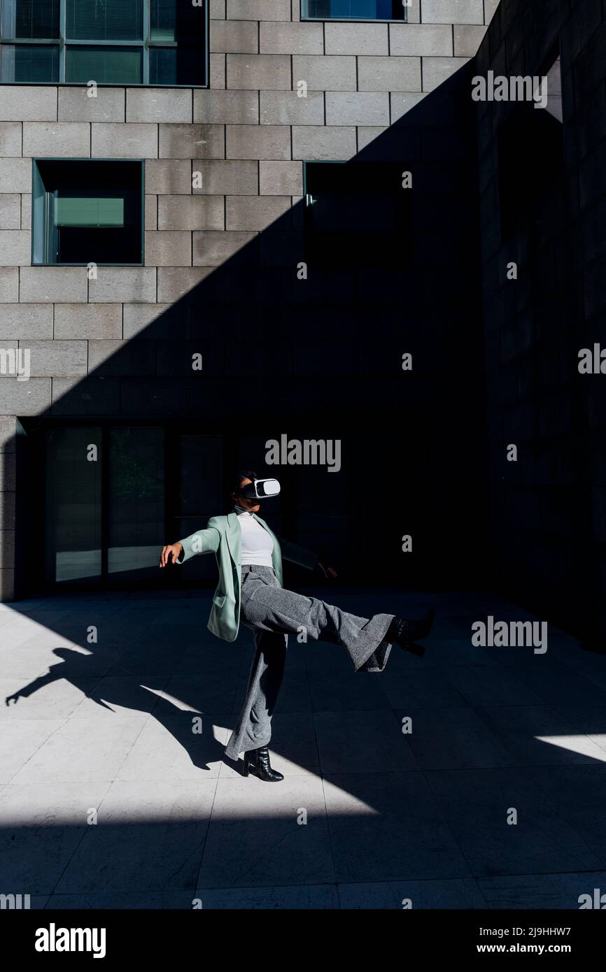 Junge Geschäftsfrau balanciert auf einem Bein durch Bürogebäude Stockfoto