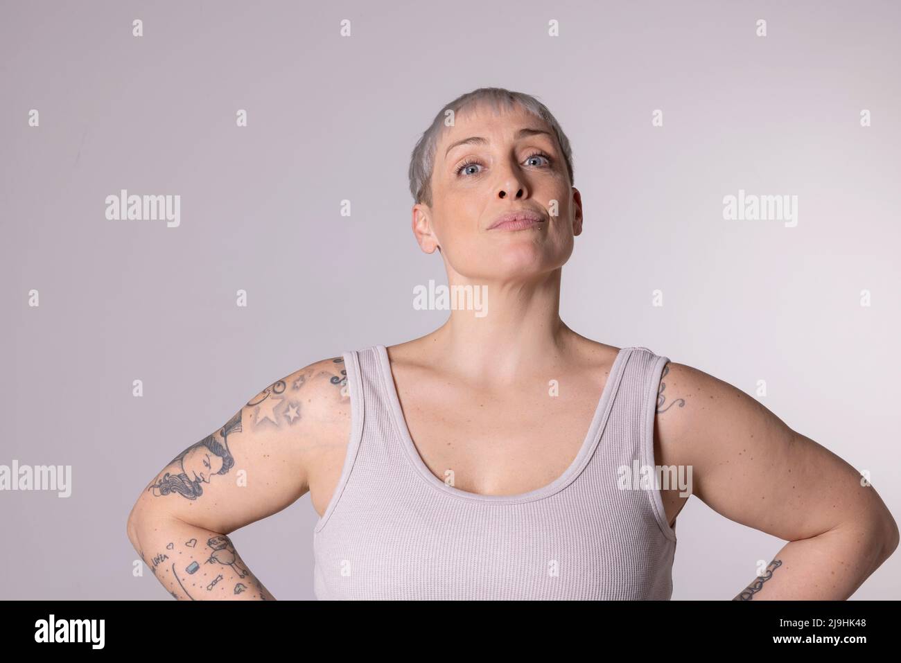 Frau mit kurzen Haaren, die vor weißem Hintergrund steht Stockfoto