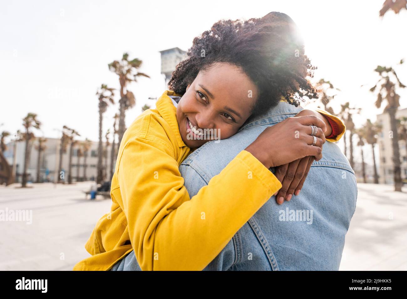 Glückliche Frau mit Afro-Frisur umarmenden Mann an sonnigen Tag Stockfoto