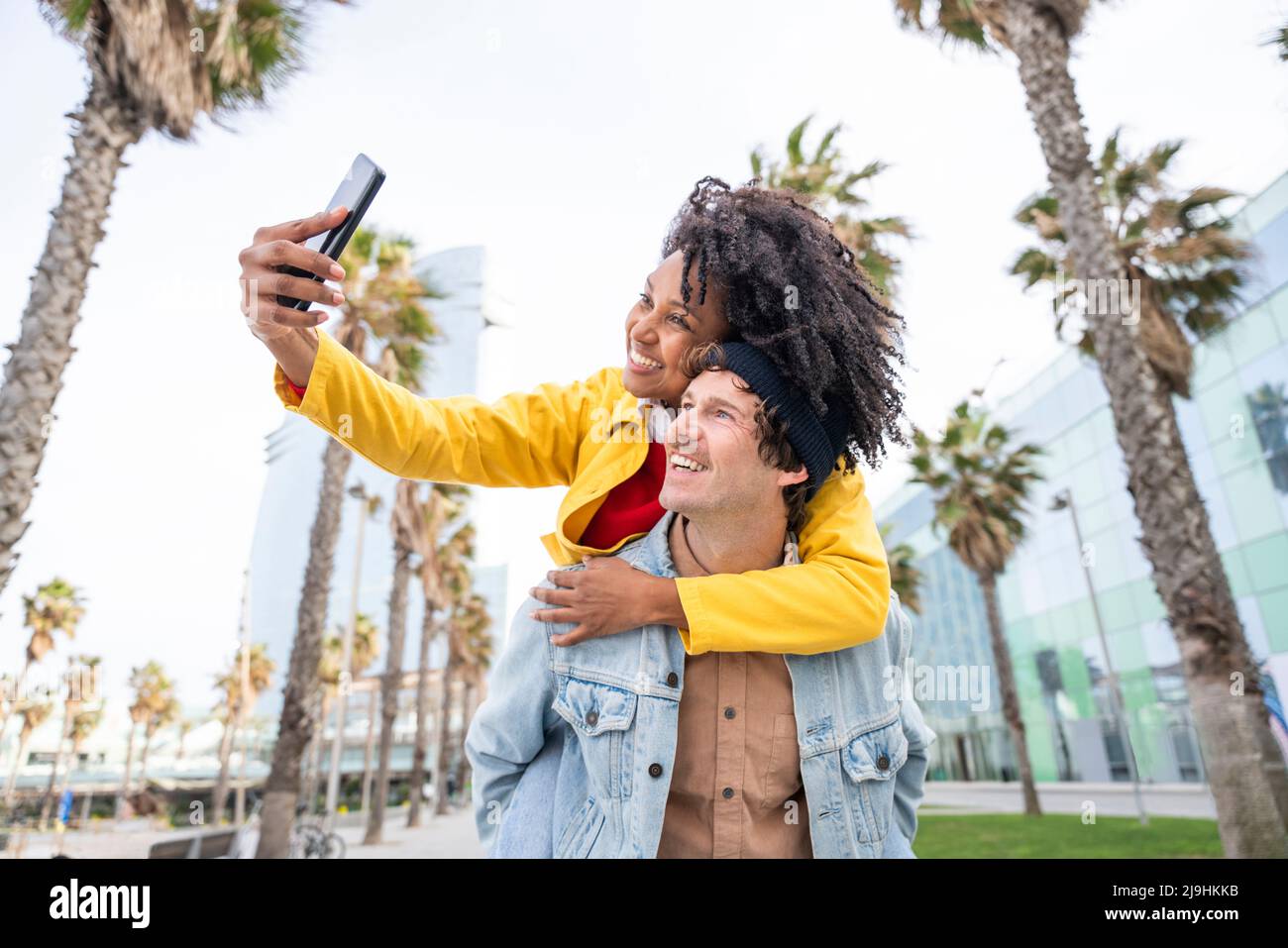 Lächelnde Frau, die Selfie mit einem Mann macht, der Huckepack fährt Stockfoto