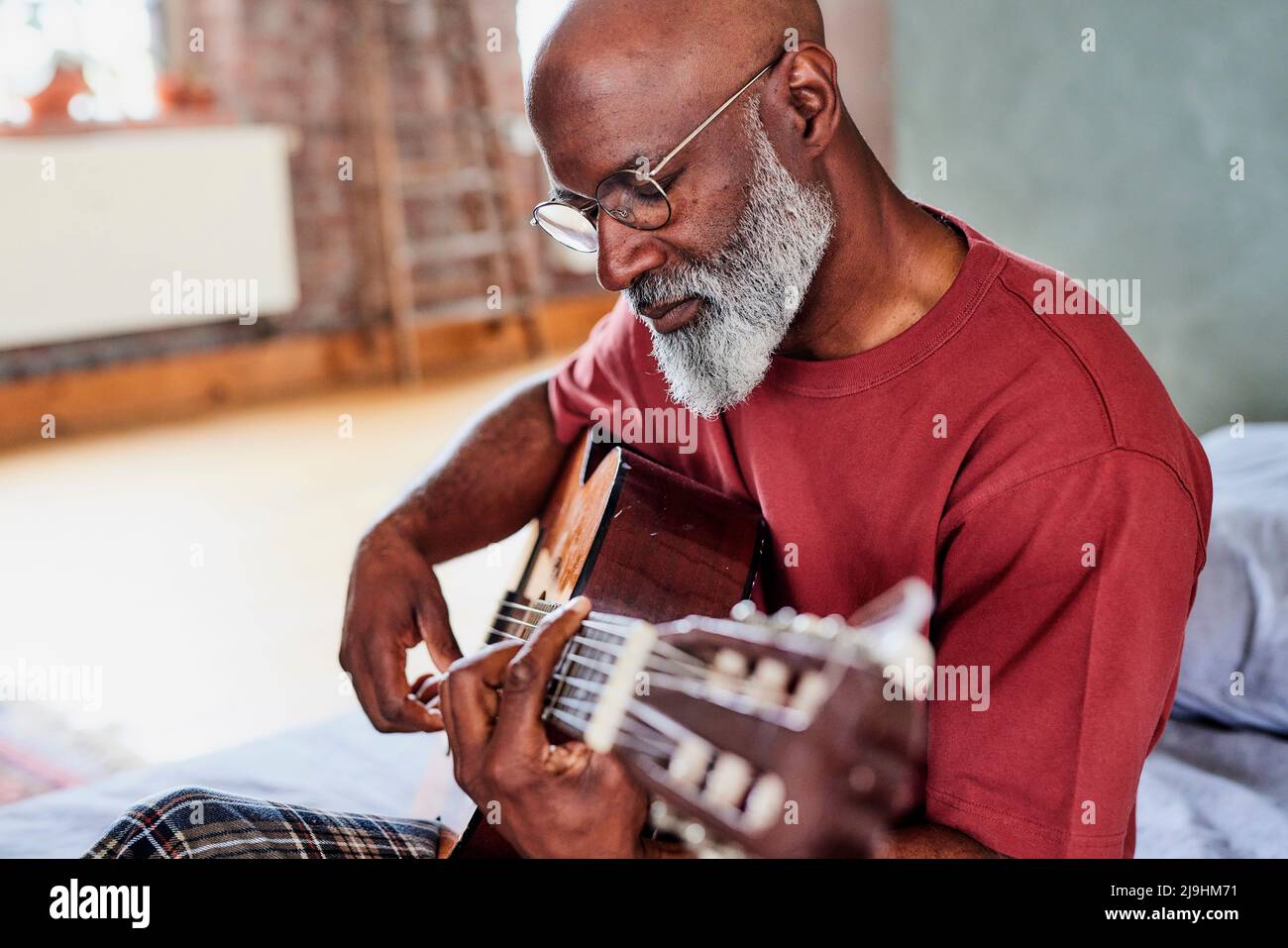 Mann mit Brille, der zu Hause Gitarre spielt Stockfoto