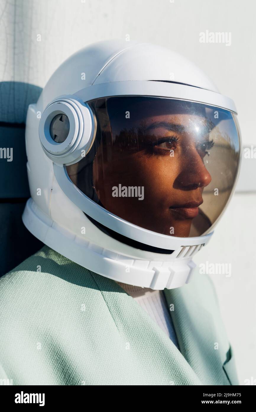 Kontemplative Geschäftsfrau mit Astronautenhelm Stockfoto