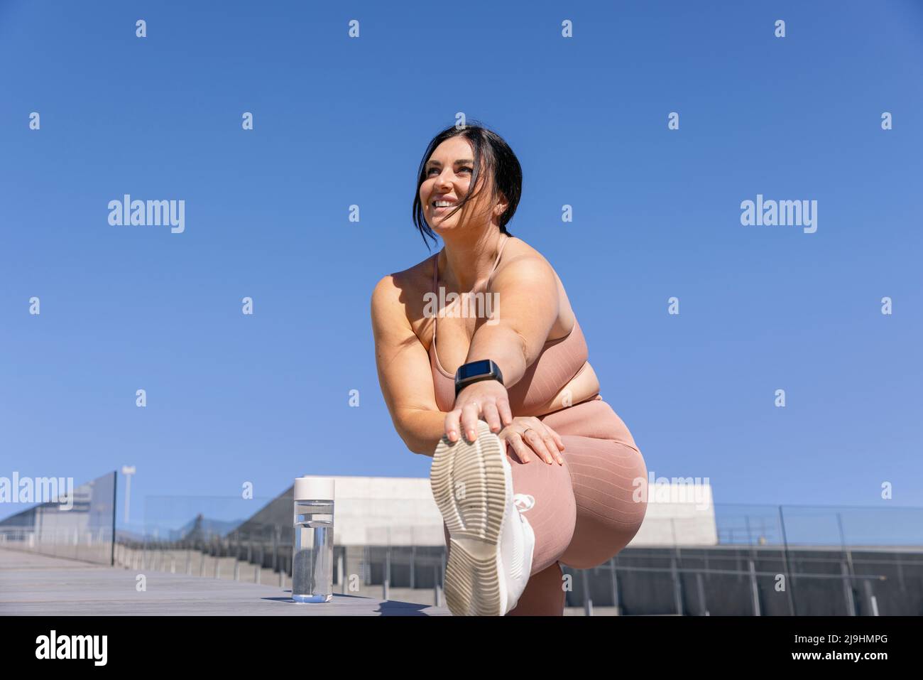 Lächelnde kurvige Frau macht Dehnübungen auf Treppen Stockfoto