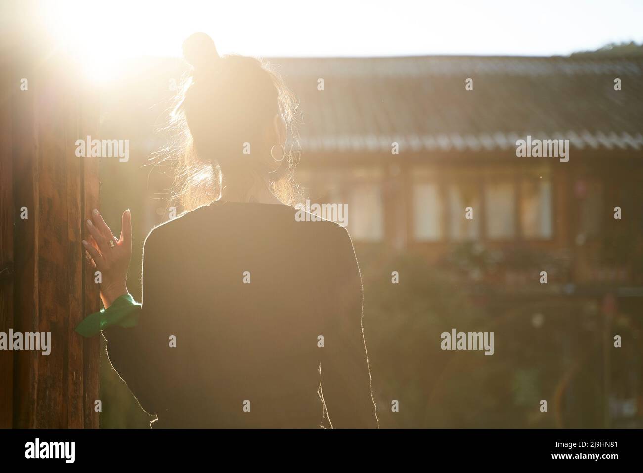 Rückansicht einer asiatischen Frau, die im Sonnenlicht steht und die Aussicht betrachtet Stockfoto