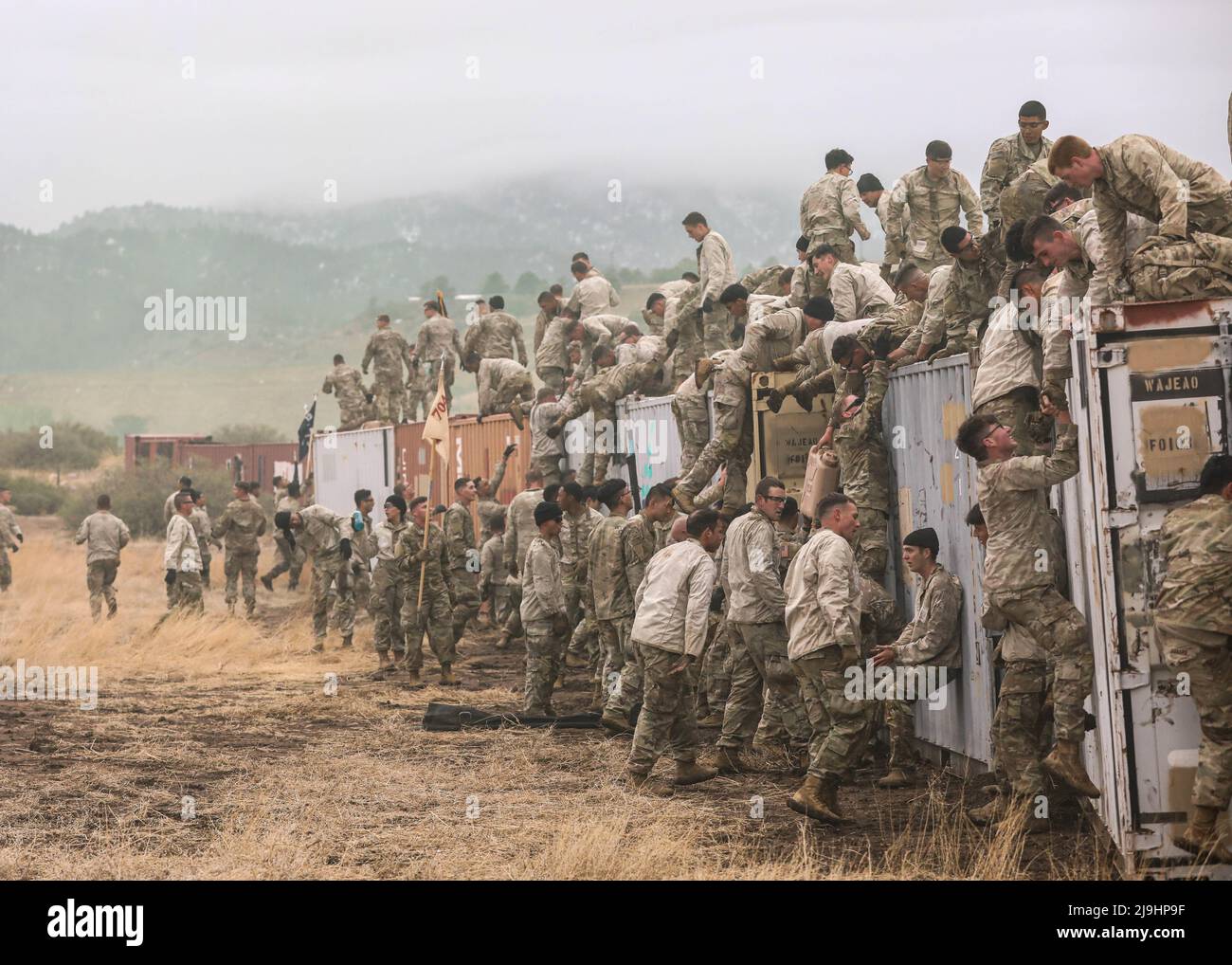 Fort Carson, Usa. 23.. Mai 2022. Soldaten der US-Armee, die der Infanterie-Division 4. zugewiesen wurden, helfen beim Utah Beach Challenge Event am 23. Mai 2022 in Fort Carson, Colorado, einander über eine schlammige Containerwand zu stoßen. Die Veranstaltung während der Ivy Week erfordert Teams von Soldaten, einen 300-Pfund-Reifen über einen schlammigen Hindernisparcours zu tragen. Kredit: SSGT. Matthew Lumagui/USA Army/Alamy Live News Stockfoto