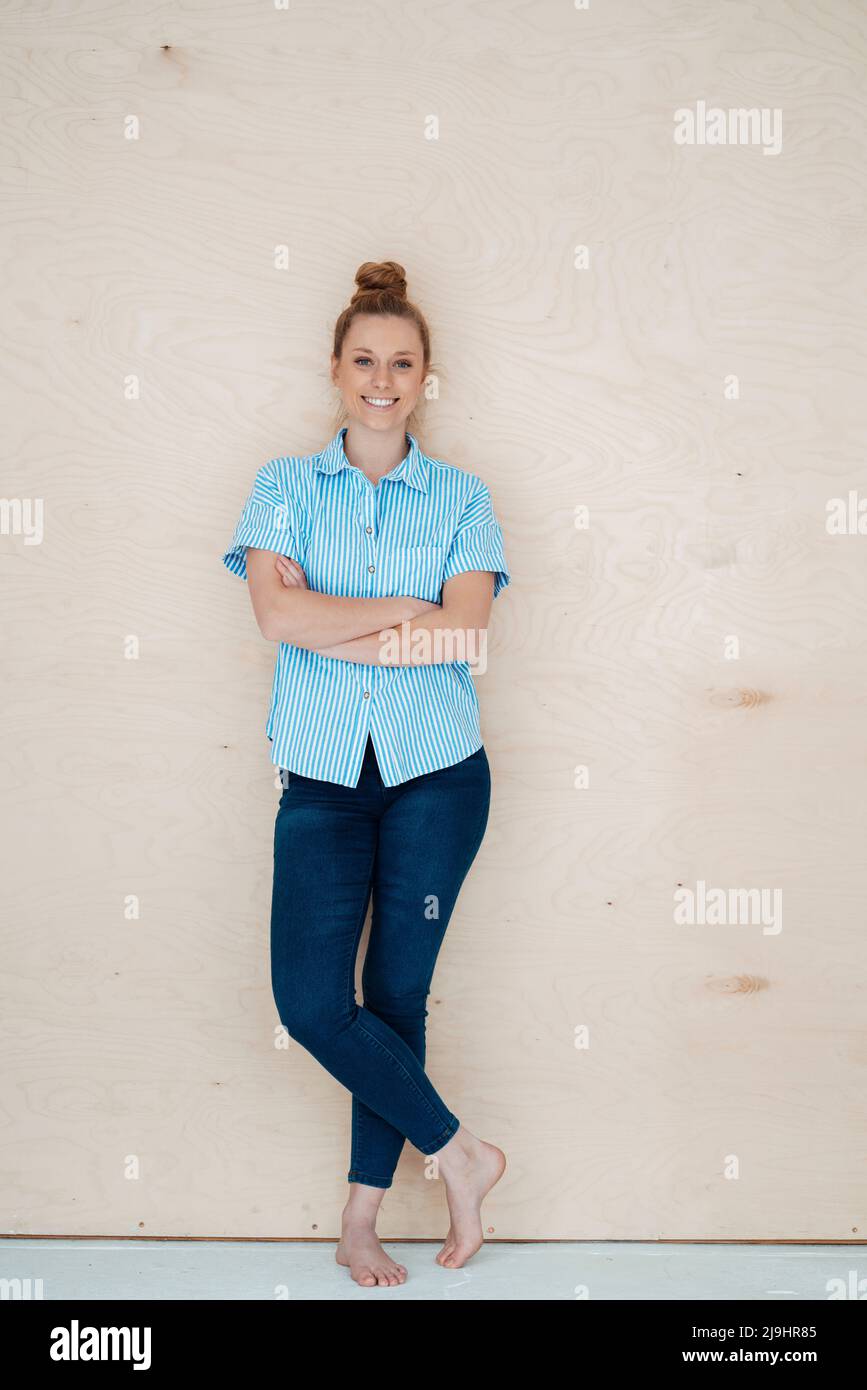 Geschäftsfrau mit gekreuzten Armen, die vor der Wand steht Stockfoto