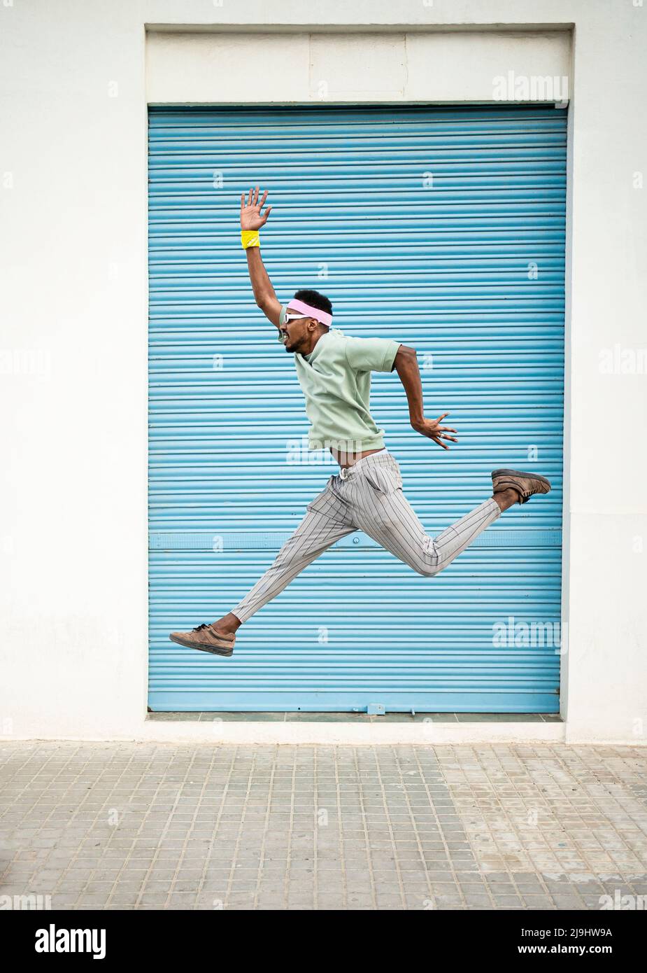 Verspielter junger Mann, der mitten in der Luft springt und die Hand auf dem Fußpfad angehoben hat Stockfoto