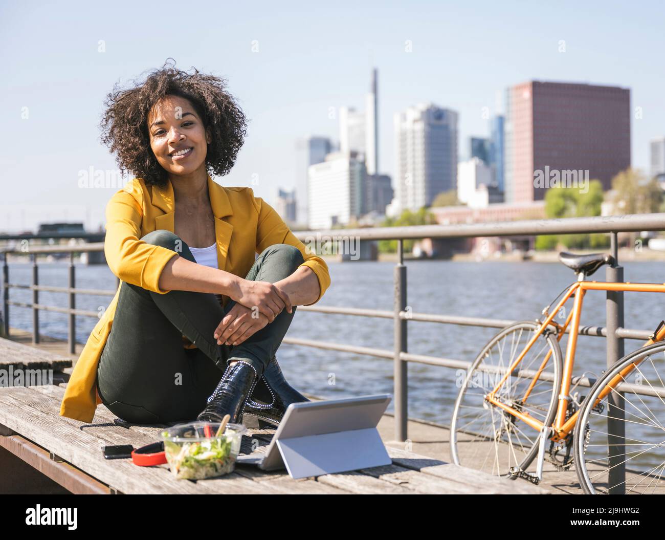 Junge Geschäftsfrau mit Essen und Laptop von River Main Stockfoto